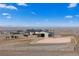 Aerial view of a home with an equestrian facility, including a barn and horse riding arena with mountain views at 7600 Patrick Trl, Elizabeth, CO 80107