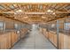 Spacious horse barn with wooden stalls, concrete floor, and high ceilings for ample ventilation and natural light at 7600 Patrick Trl, Elizabeth, CO 80107