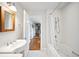 White bathroom with white tile walls, a tub, a modern sink, and a wood framed mirror at 141 N Gilpin St, Denver, CO 80218