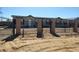 View of property behind a decorative iron fence with brick columns and a gravel driveway at 15460 Casler Ave, Fort Lupton, CO 80136