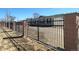 View of property behind a decorative iron fence with brick columns and a gravel driveway at 15460 Casler Ave, Fort Lupton, CO 80136