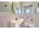 Bright bathroom features a vanity with a vessel sink, an oval mirror, and tiled shower tub at 8060 Meade St, Westminster, CO 80031