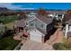 Aerial view of a gray home with a brick foundation, complemented by lush landscaping and a scenic mountain backdrop at 6271 Mcintyre Way, Golden, CO 80403