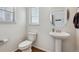 Cozy powder room with white fixtures, pedestal sink, and stylish round mirror at 1160 Acadia Cir, Erie, CO 80516