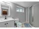 Bathroom with white vanity, tiled floor, enclosed shower, and large mirror with modern lighting fixtures at 5075 Weeping Willow Cir, Highlands Ranch, CO 80130