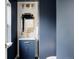 Stylish powder room featuring patterned wallpaper, gold fixtures, and a vanity with blue cabinet at 3473 Beeler St, Denver, CO 80238
