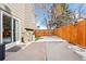 A snow-covered concrete patio with a wooden fence and access to the house at 12844 W Cross Dr, Littleton, CO 80127