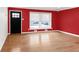 Empty living room featuring hardwood floors, red accent wall and large window at 4545 E Harvard Ave, Denver, CO 80222