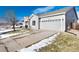 Gray house with a two-car garage and driveway, partially covered in snow at 3564 S Jebel Cir, Aurora, CO 80013