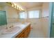 Bright bathroom featuring double sinks, tiled floors, and a glass-enclosed shower at 3000 S Newland St, Denver, CO 80227