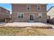 Back of the home featuring neutral siding, a stone accent wall, and a concrete patio at 6472 N Dunkirk Ct, Aurora, CO 80019