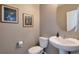 Elegant half bath featuring a pedestal sink, decorative mirror, and stylish wall art at 6472 N Dunkirk Ct, Aurora, CO 80019