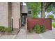 Exterior entryway of a charming home featuring a brick accent wall and a small courtyard with greenery at 1254 S Yosemite Way # 99, Denver, CO 80247