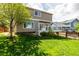 A lush green backyard featuring a well-maintained lawn, mature trees, and a deck, perfect for relaxation at 1041 Riddlewood Rd, Highlands Ranch, CO 80129