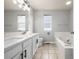 Bright bathroom features double sinks, quartz countertops, and a soaking tub under a window at 1041 Riddlewood Rd, Highlands Ranch, CO 80129