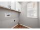 This laundry room has wooden laminate floors, upper cabinets and a window for natural light at 1041 Riddlewood Rd, Highlands Ranch, CO 80129