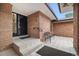Inviting front entrance with brick facade, tiled patio, and secure metal gate at 6300 W Mansfield Ave # 61, Denver, CO 80235