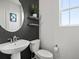 Modern powder room with pedestal sink, round mirror, and stylish decor at 9446 Quintero St, Commerce City, CO 80022