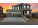 Two-story home with a three-car garage and a charming front porch, enhanced by a colorful sunset sky at 9446 Quintero St, Commerce City, CO 80022