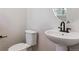 Modern powder room features a pedestal sink, toilet, and black hardware at 14123 Deertrack Ln, Parker, CO 80134