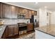 Well-equipped kitchen with stainless steel appliances, dark cabinets, granite countertops, and tile backsplash at 16201 Lanceleaf Pl, Parker, CO 80134
