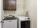 Functional laundry room with modern washer and dryer, overhead shelving, and convenient ironing board storage at 16201 Lanceleaf Pl, Parker, CO 80134