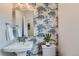 Stylish powder room with crane-patterned wallpaper, a pedestal sink, and elegant fixtures, perfect for guests at 4104 Grand Lake St, Brighton, CO 80601