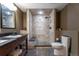 Luxurious bathroom featuring a tiled shower with built-in bench, river rock floor, and modern fixtures at 24733 E Park Crescent Dr, Aurora, CO 80016