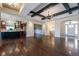 Open concept living room featuring hardwood floors, wood-beamed ceilings, and seamless kitchen access at 24733 E Park Crescent Dr, Aurora, CO 80016