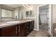 Bathroom featuring double sinks with tile countertops, wood cabinets, and a walk-in closet at 10221 Nucla St, Commerce City, CO 80022