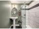 Stylish bathroom featuring a pedestal sink, modern vanity lighting, and a glass shower with a gray accent stripe at 10221 Nucla St, Commerce City, CO 80022