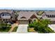 Aerial front view of a home featuring a well-kept lawn, landscape, a two-car garage and a long driveway at 10221 Nucla St, Commerce City, CO 80022