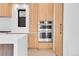Modern kitchen featuring natural wood cabinets, stainless steel appliances, and white countertops at 1491 S York St, Denver, CO 80210