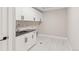 Clean laundry room featuring white cabinets, dark hardware, dark countertops, and a tiled floor at 1426 Swan Peter Dr, Berthoud, CO 80513