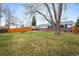 Large backyard featuring a wood fence, large trees, and patio with furniture at 9395 W Kentucky Ave, Lakewood, CO 80226