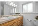 Bathroom with neutral tiled countertop, wooden vanity, and window letting in natural light at 9395 W Kentucky Ave, Lakewood, CO 80226