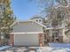 Inviting home featuring brick accents, a two-car garage, and a winter landscape at 2676 S Troy Ct, Aurora, CO 80014