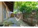 A fenced backyard showing a concrete patio and a walkway with mature trees providing ample shade at 3720 S Fairplay Way, Aurora, CO 80014