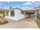 Exterior view of a single story house featuring white siding, a carport, and well-lit windows at 7760 Magnolia St, Commerce City, CO 80022