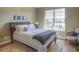 Comfortable bedroom with a well-made bed, framed pictures, an upholstered chair, and natural light from a large window at 11932 W Long Cir # 202, Littleton, CO 80127