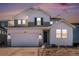 Two-story home with gray and white siding, a two-car garage, and landscaping at dusk at 3589 Rucksack Ct, Castle Rock, CO 80108