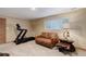 Cozy basement featuring a treadmill, sofa, and rustic-style table with soft neutral carpet at 9852 Zephyr Dr, Broomfield, CO 80021