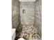 Remodeled shower with stone pebble flooring and gray tiled walls, creating a spa-like retreat at 16841 E Mansfield Cir, Aurora, CO 80013