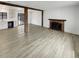 Open-concept living room with a brick fireplace, wood beams, and wood-look floors at 16841 E Mansfield Cir, Aurora, CO 80013