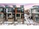 Modern three-story townhome with attached two-car garage, snow covered landscaping at 6860 E Lowry Blvd, Denver, CO 80230