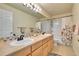 Well-lit bathroom with double sinks, long vanity, and tiled shower-tub combination at 10653 W Parkhill Dr, Littleton, CO 80127