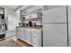 Kitchenette with open shelving, light cabinets, stainless appliances, and a light-filled window at 10653 W Parkhill Dr, Littleton, CO 80127