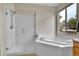 Bright bathroom featuring a glass shower, soaking tub, and exterior view at 10653 W Parkhill Dr, Littleton, CO 80127