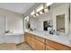 Main bathroom featuring dual sinks, large mirror, soaking tub, and generous natural light at 10653 W Parkhill Dr, Littleton, CO 80127