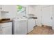 Bright laundry room with washer, dryer, upper and lower cabinets, sink, and tile floor at 4850 S Kittredge St, Aurora, CO 80015